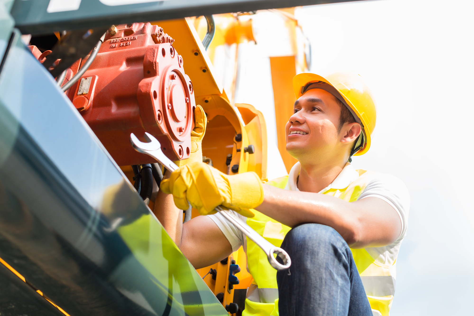 Mechanic is repairing an engine by holding a wrench with his right hand.