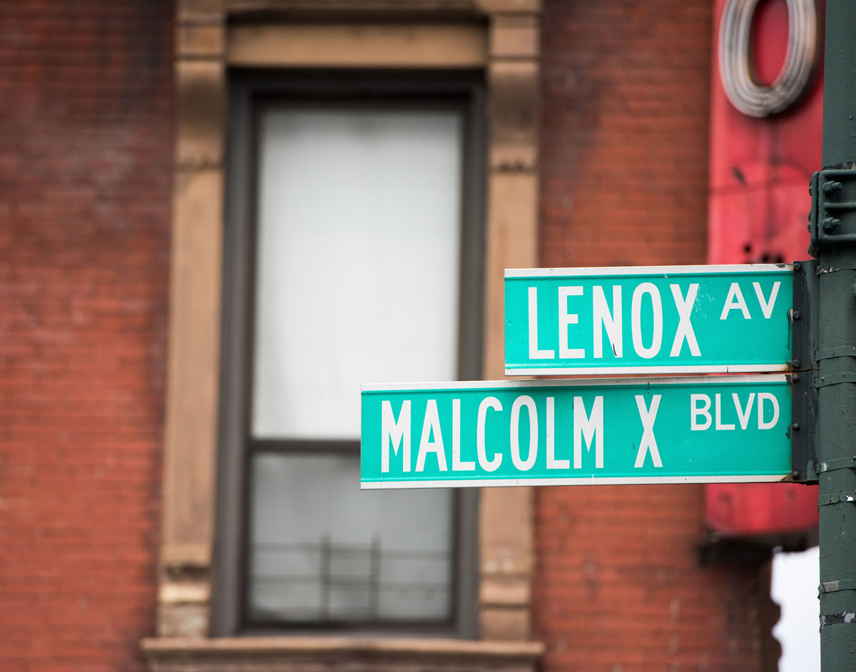 A Green color street sign in Harlem. The signs read Lenox Avenue and in the bottom sign in Green color it read Malcolm X Blvd.