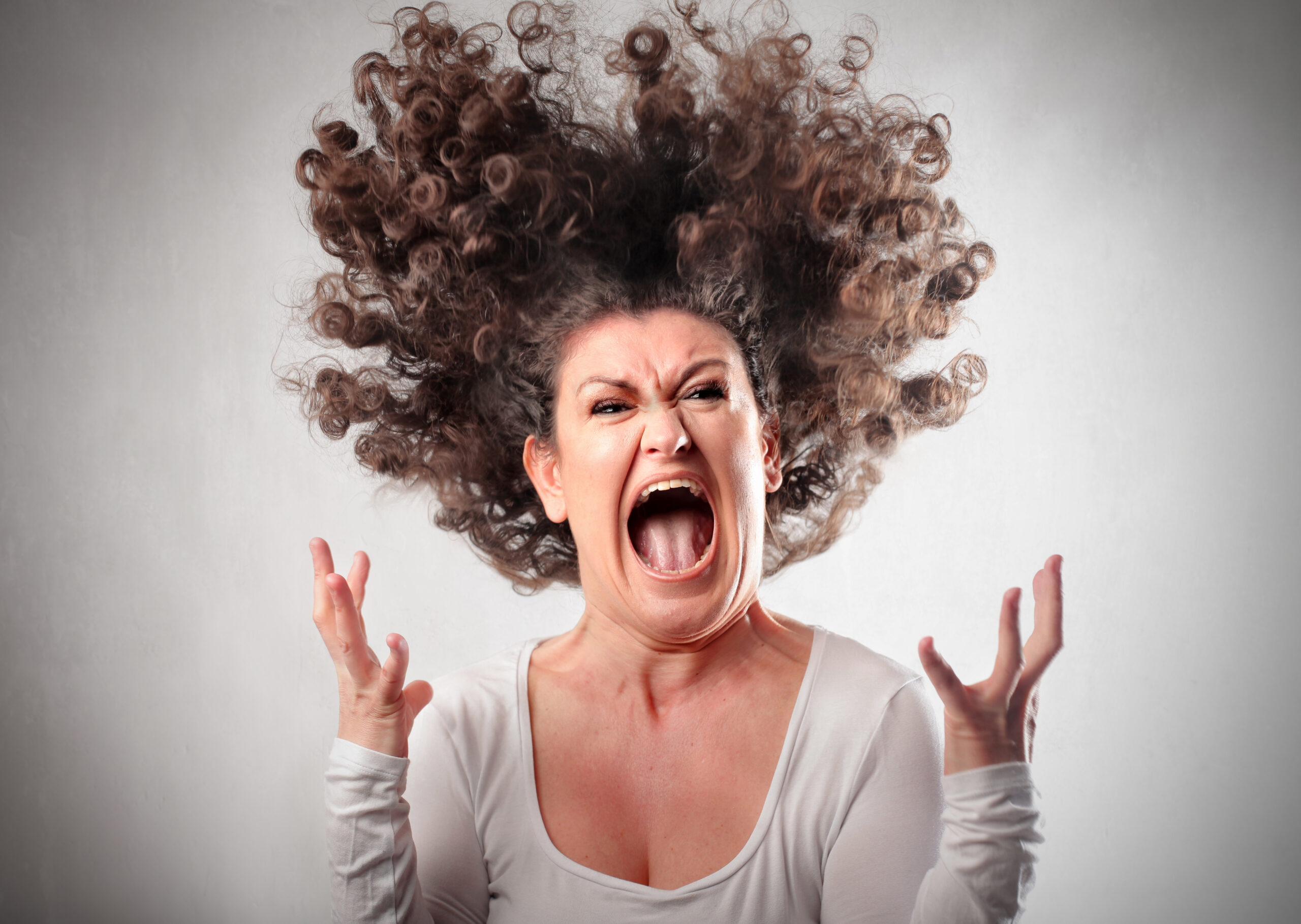 Angry woman holding her hands up in anger while screaming